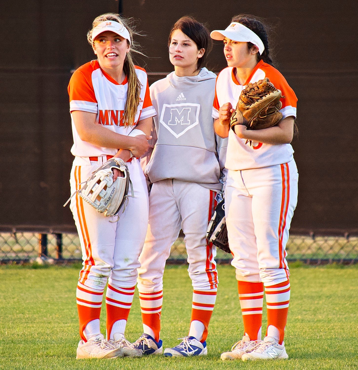 As the winds blew through and the temperature dropped, it was a struggle to stay warm in between the action. Here, senior outfielders Alyssa Lankford and Alana Galaz show signs of chilliness, while Kenleigh Aguirre is warmer in her pullover.  [more thrills, chills]